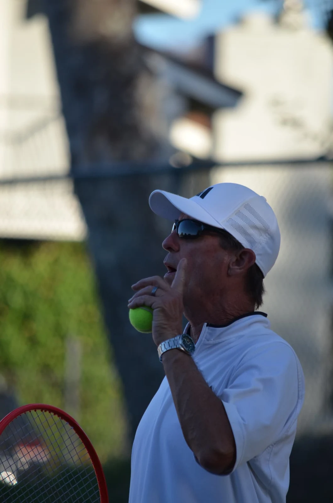 Coach Thor Schreck holding a tennis ball and racket on the Concord courts